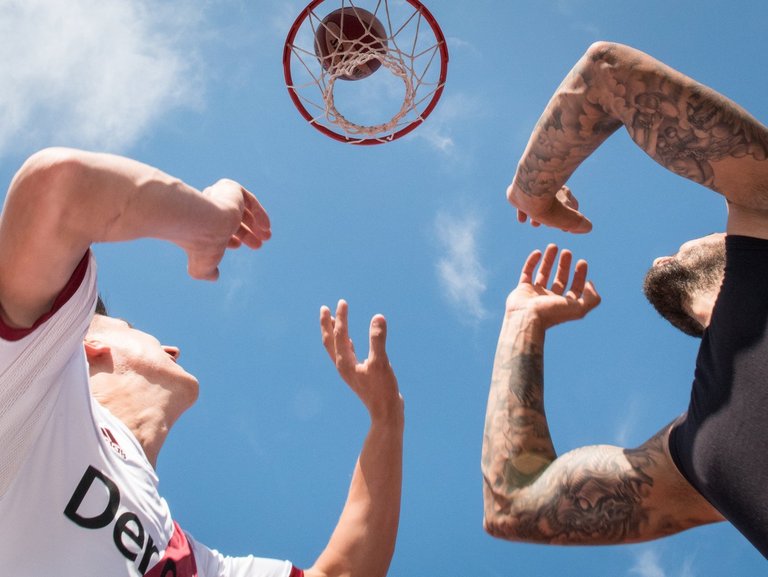 Nahaufnahme beim Sport: zwei Männer unter dem Basketballkorb - der Ball scheint gerade ins Netz zu gehen