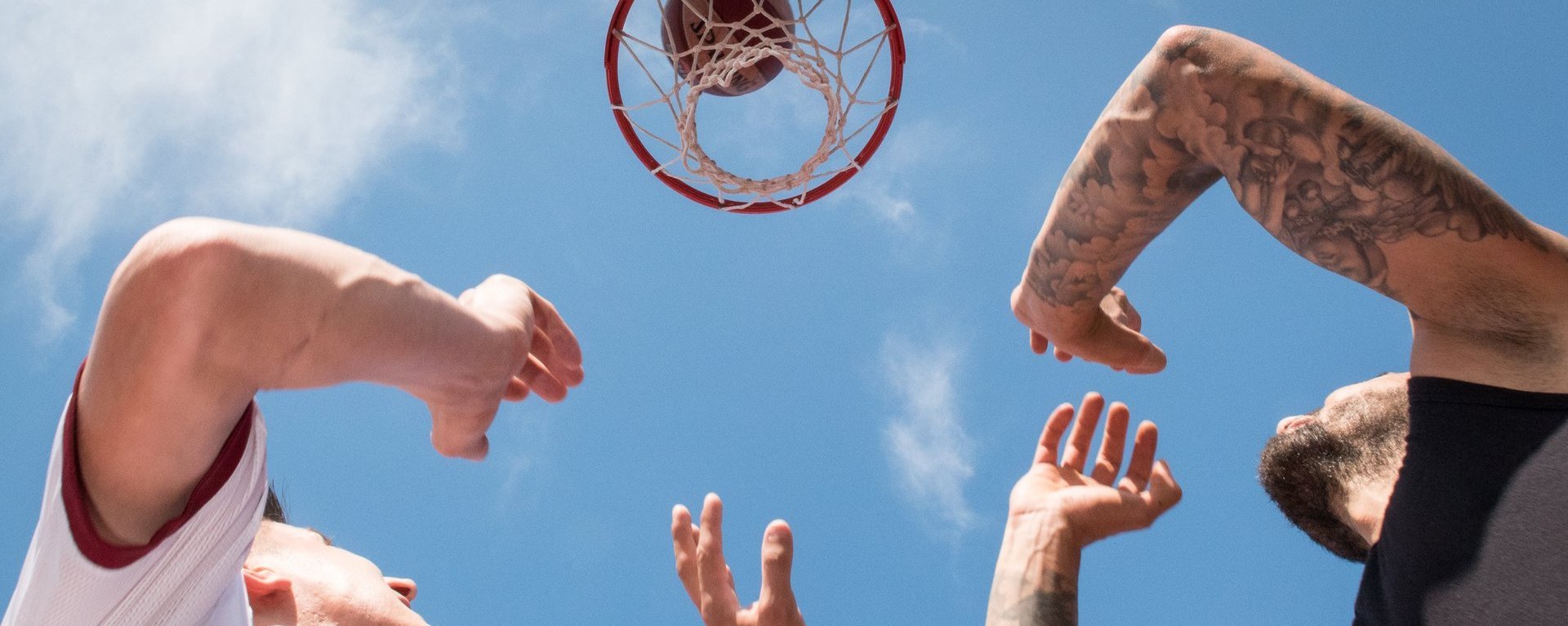 Nahaufnahme beim Sport: zwei Männer unter dem Basketballkorb - der Ball scheint gerade ins Netz zu gehen