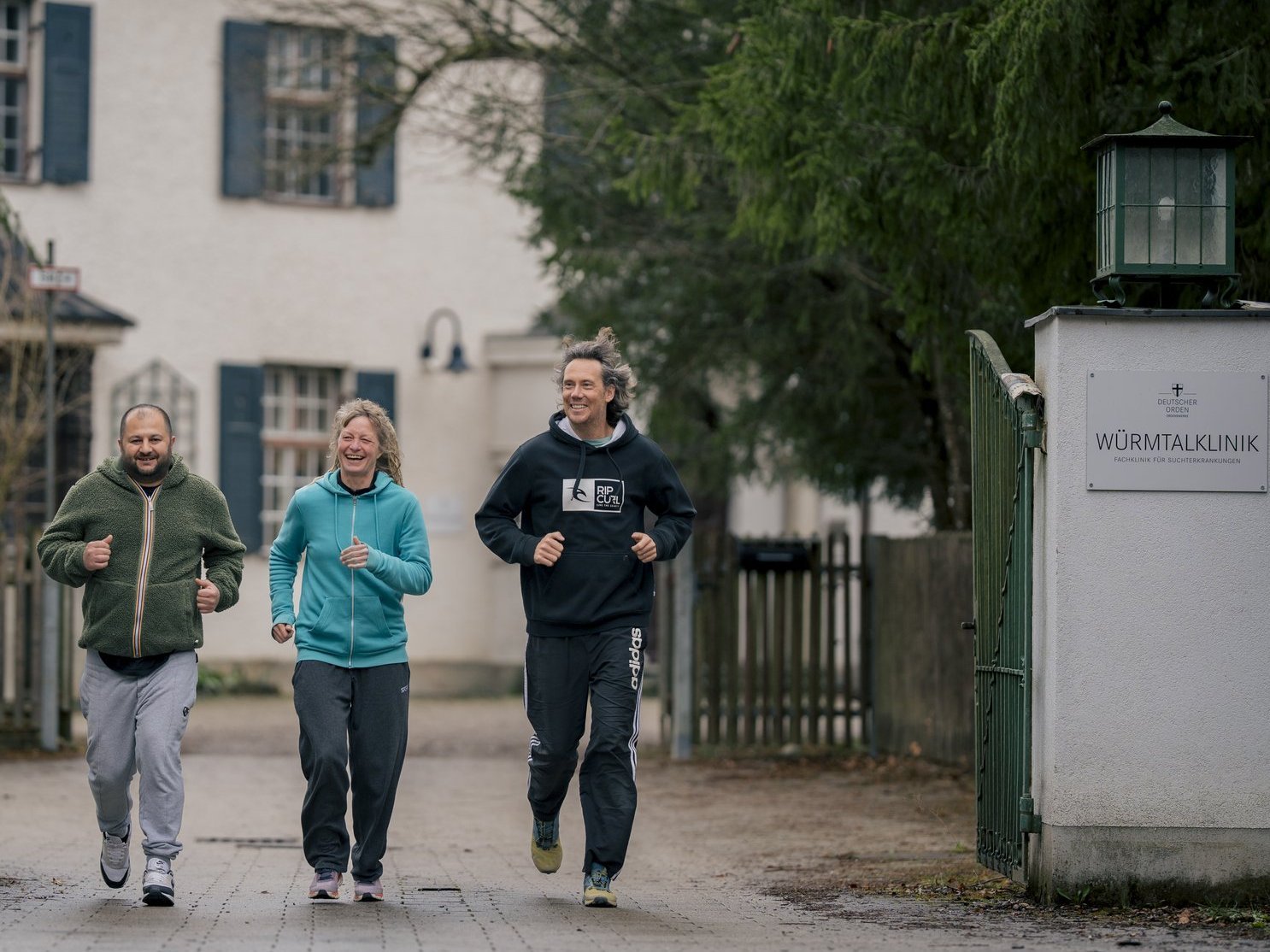 Drei Menschen in Sportkleidung laufen auf die Kamera zu.