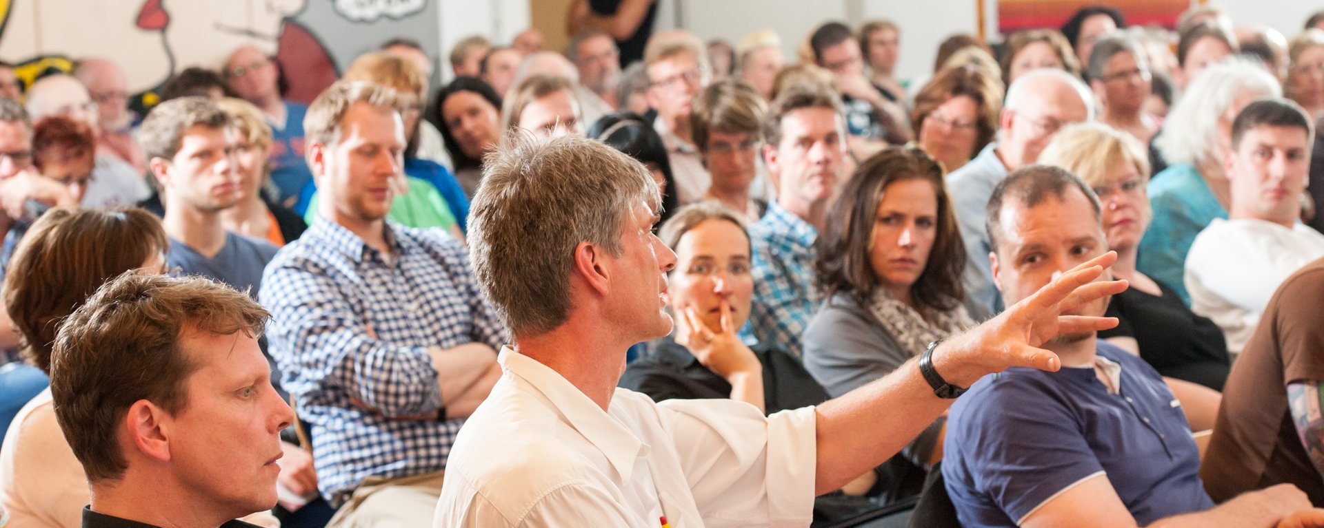 Vortrag im voll besetzten Saal: ein Mann aus dem Publikum spricht gerade